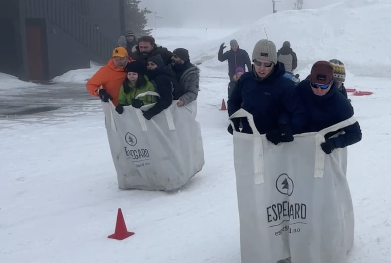 Teambuilding aktivitet der kollegaer samarbeider om oppgaver rundt et bord.